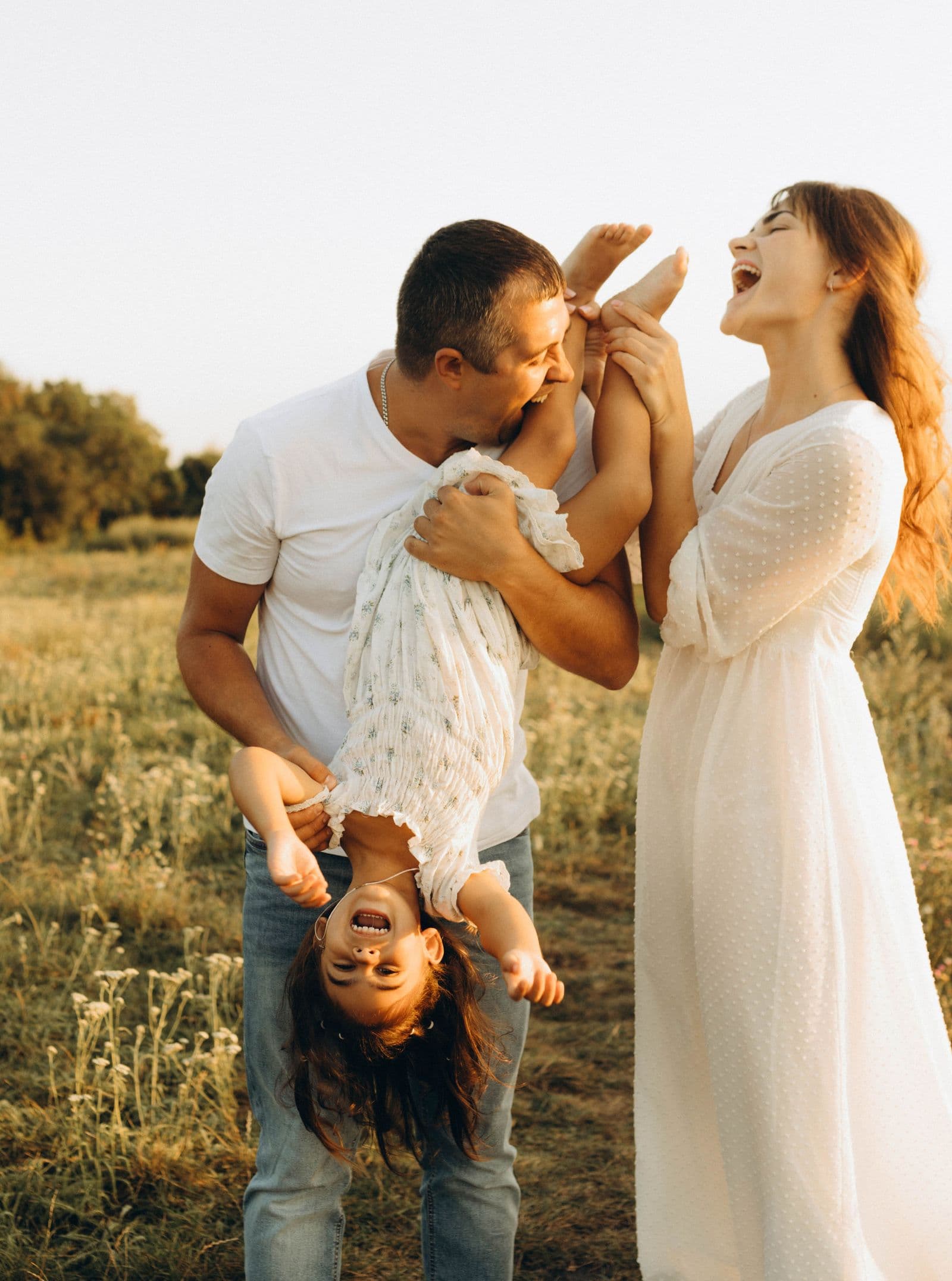 Parents playing with their daughter in a sunny field