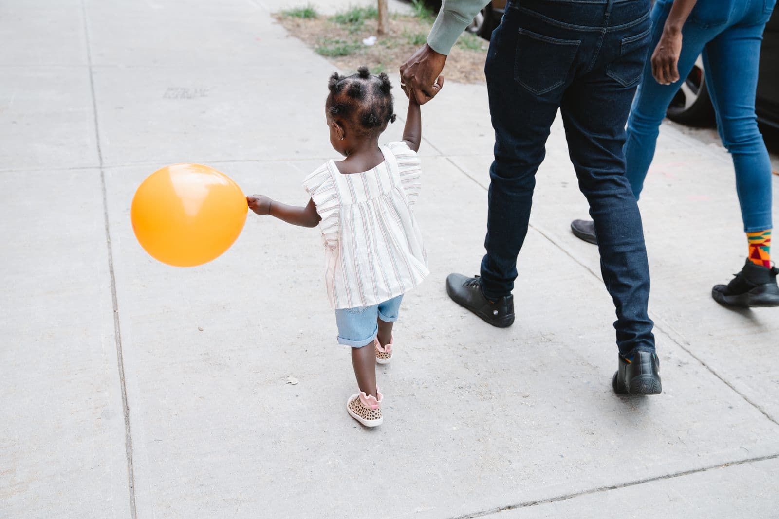 Parents walking hand in hand with their young daughter